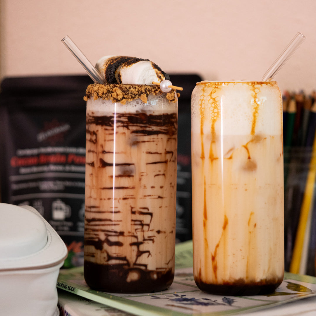 Two iced mushroom coffee drinks with whipped cream and toppings on a table.