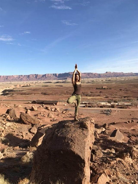 Confident woman doing tree pose on a huge boulder in the desert after completing the 7 day lion's milk challenge
