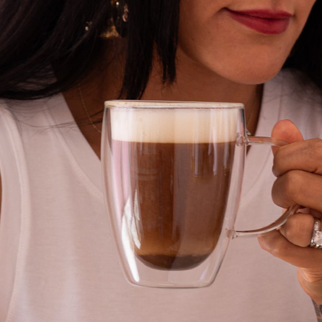 woman holding a cup of mushroom coffee without fillers in a clear glass mug
