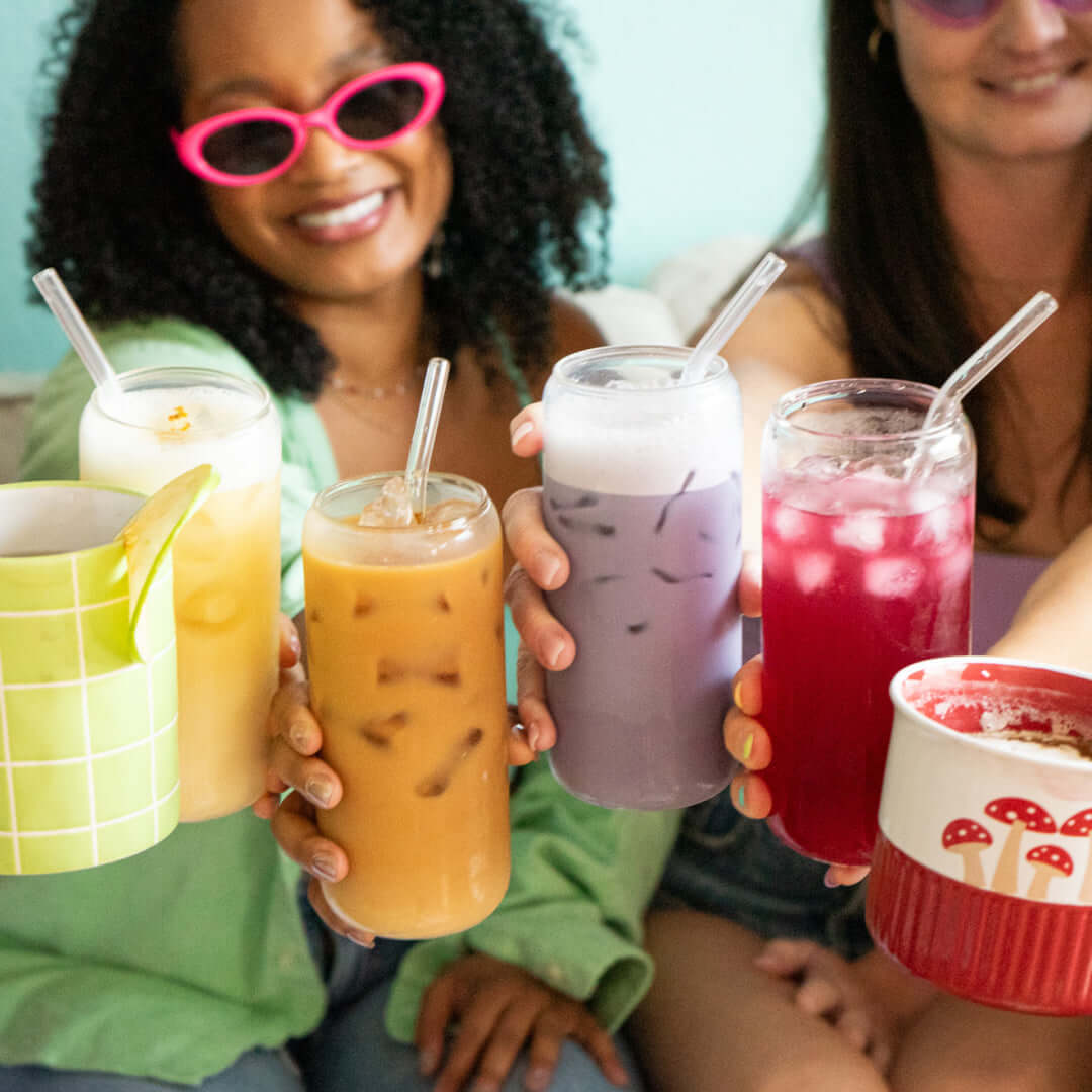 Friends holding colorful iced and hot mushroom lattes and mocktails from ZPlantMagic, including flavors like chocolate, coffee, chai, ube, berry, apple and more.