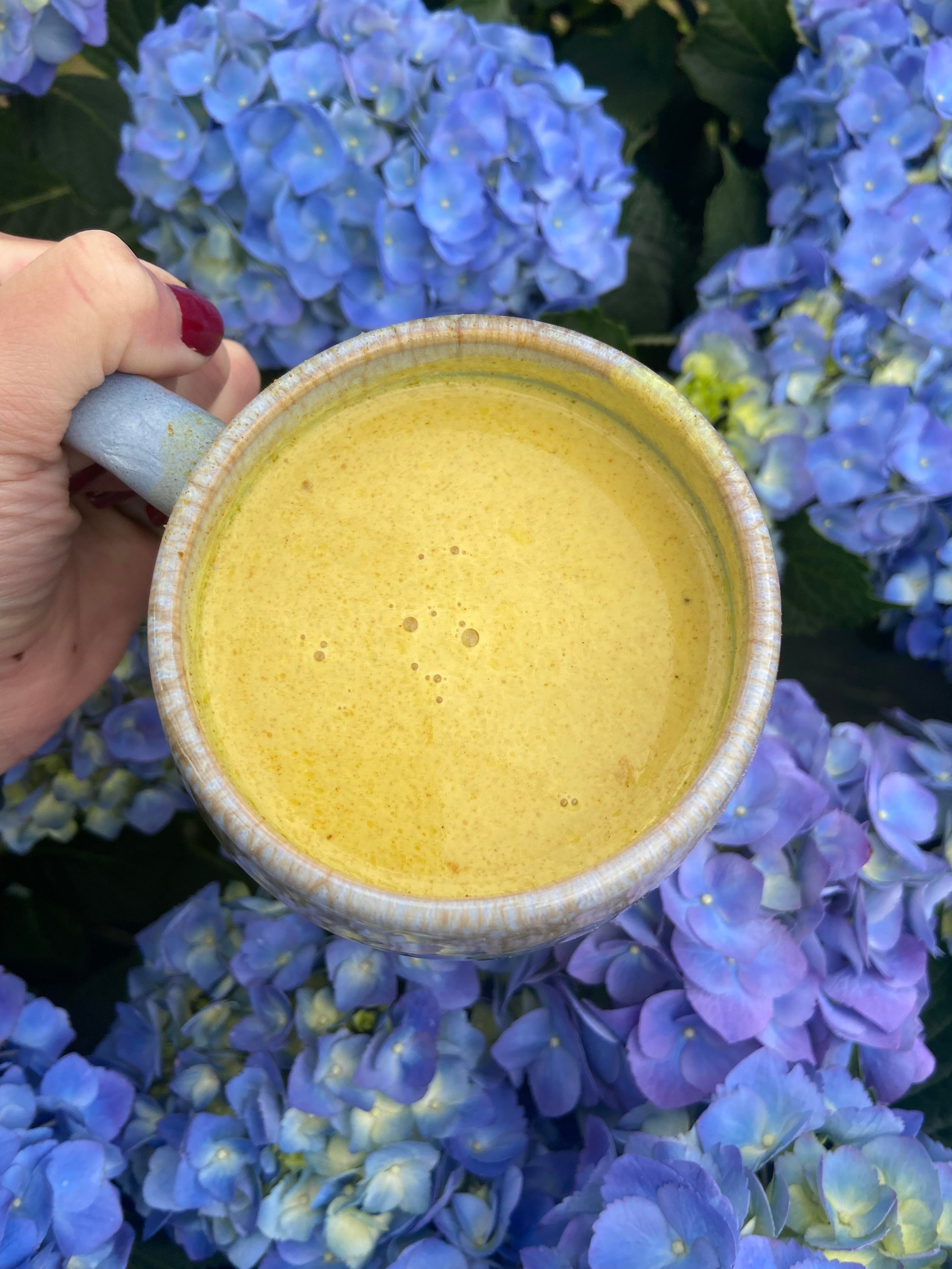 Golden milk turmeric herbal latte in a mug, caffeine-free wellness drink made with mushrooms and herbs