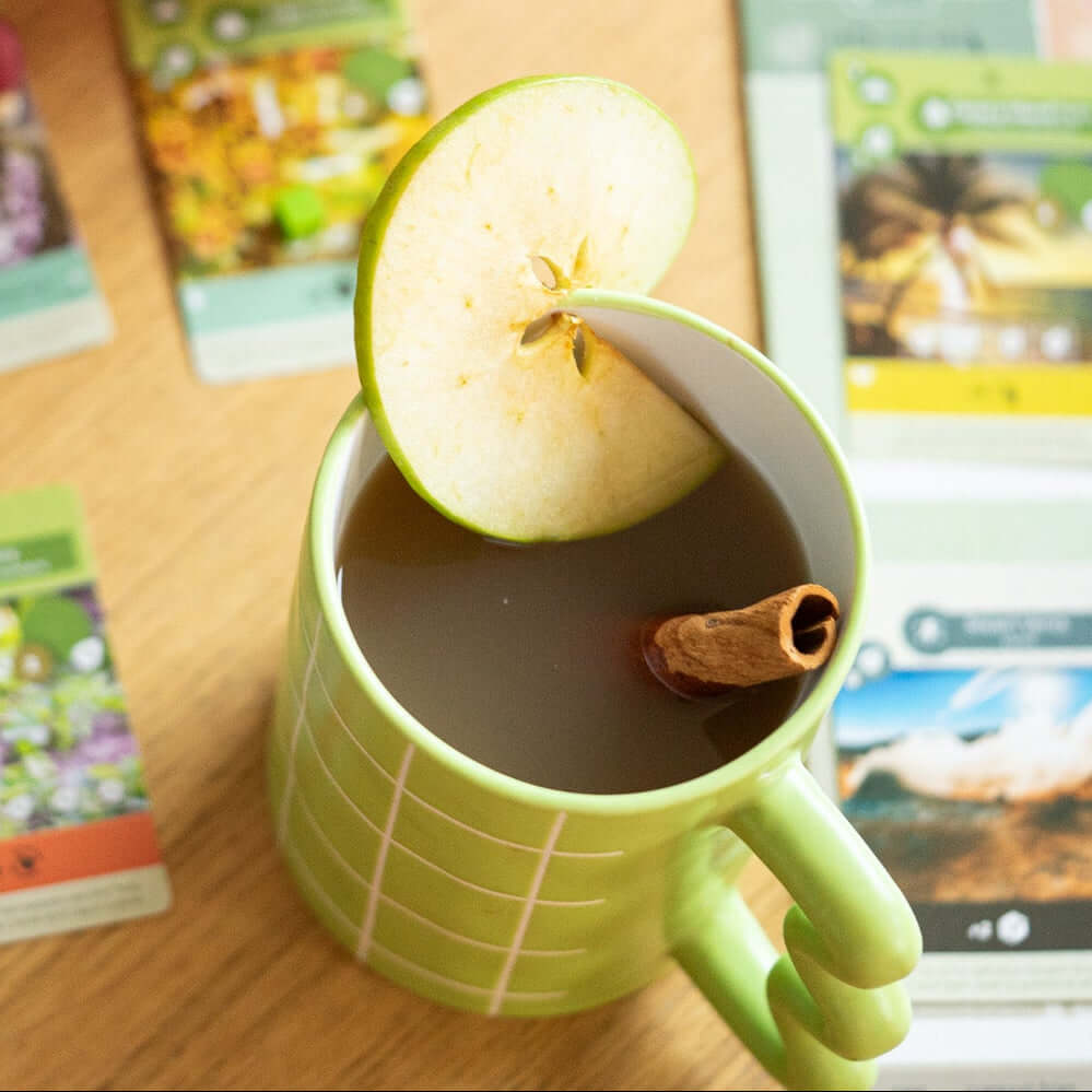 Mellow Apple herbal blend prepared as a warm apple cider with cinnamon and fresh apple slice for a cozy game night treat