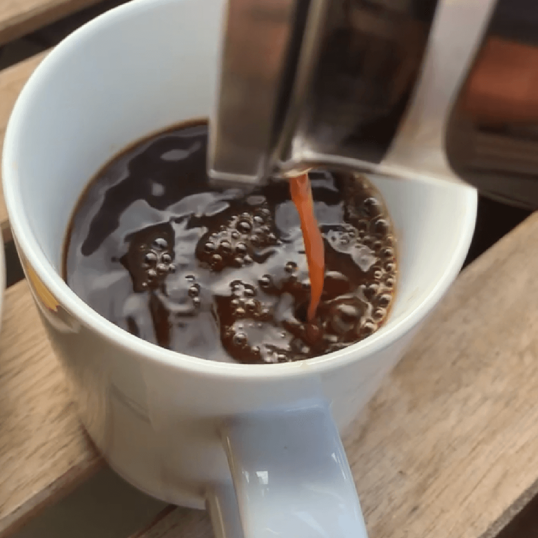 Pouring hot caffeine-free mushroom herbal coffee into a mug during a morning brewing ritual