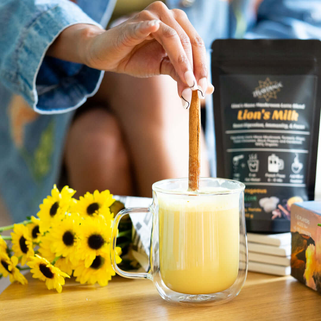 Lion's Milk golden mushroom latte being stirred with cinnamon for a cozy, caffeine-free wellness ritual